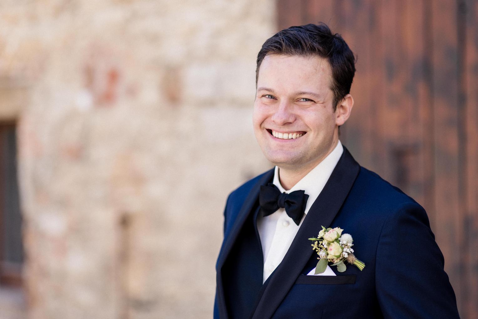 Lachendes Portrait des Bräutigams mit Fliege und Anstecker