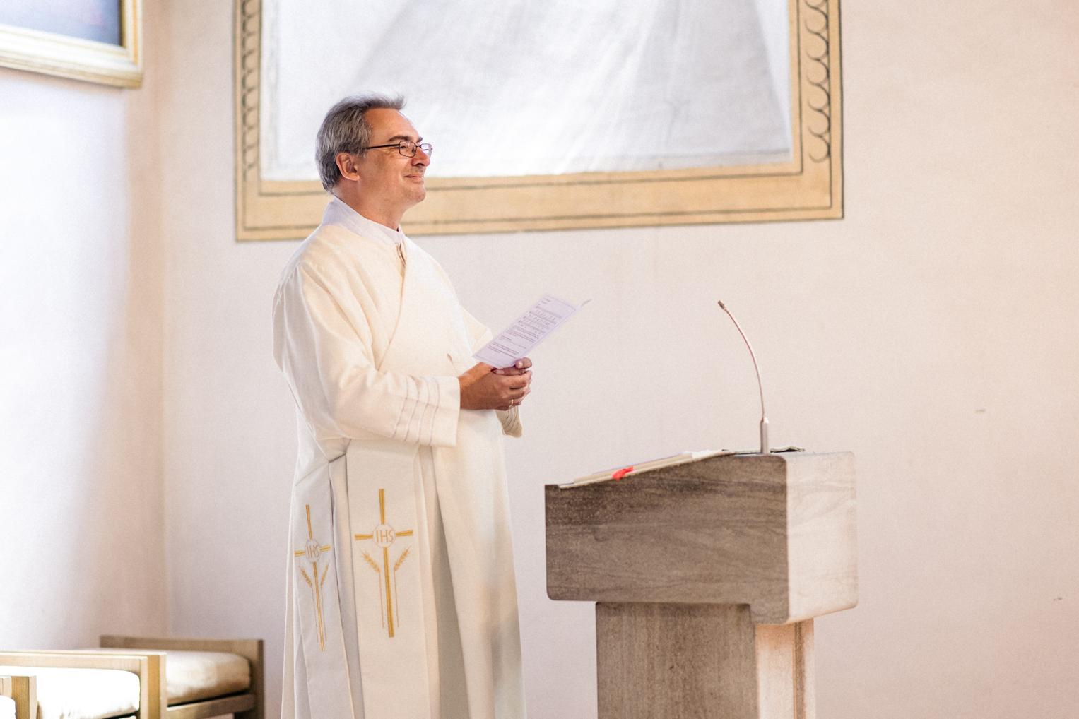 Pfarrer spricht freundlich zum Brautpaar in der Kirche