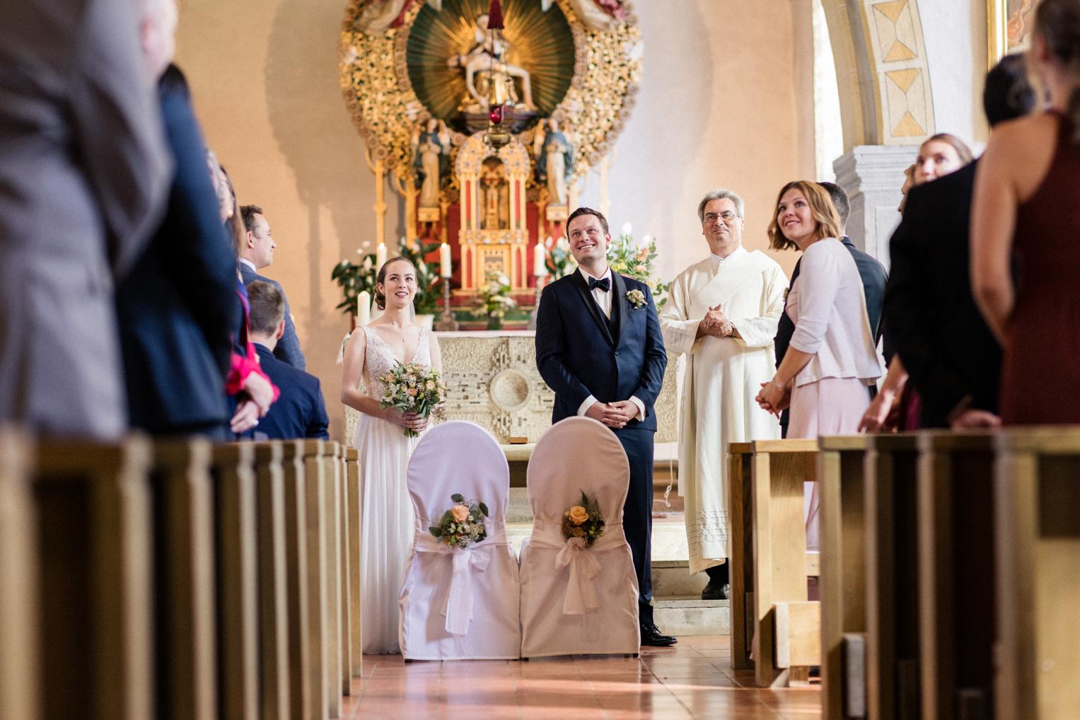 Brautpaar geht strahlend Hand in Hand zum Kirchenausgang