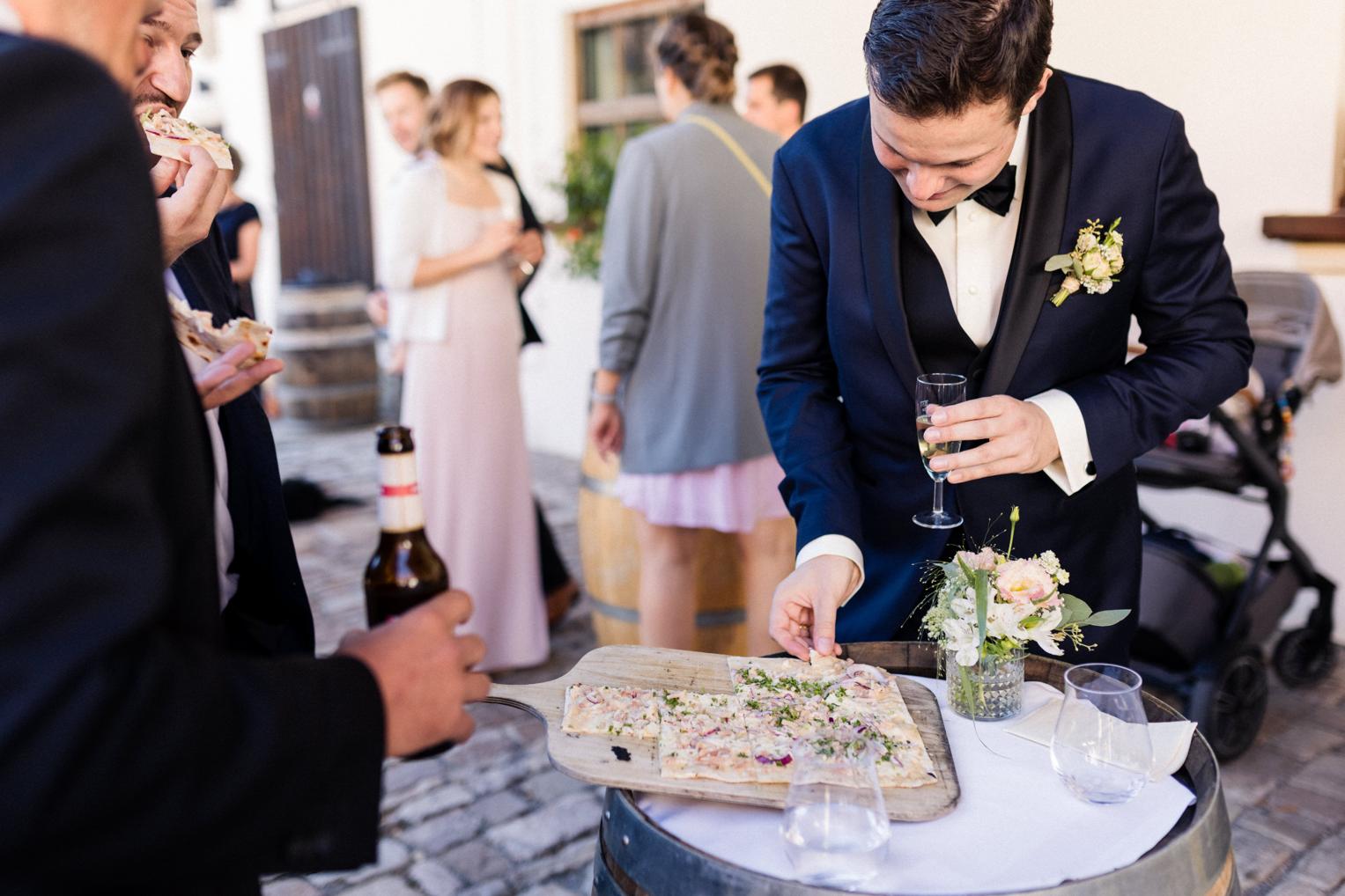 Bräutigam reicht Flammkuchen am Weinfass beim Sektempfang