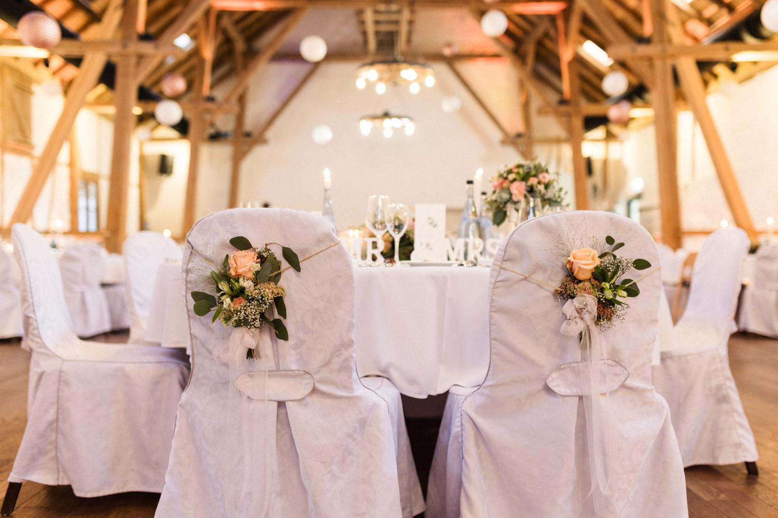 Mr und Mrs Stühle mit Rosenschmuck am Brauttisch im Festsaal