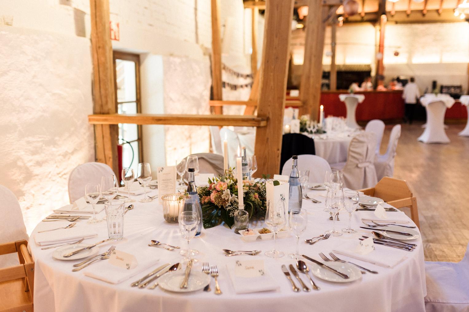 Runder Hochzeitstisch mit Kerzen vor Bruchsteinmauer