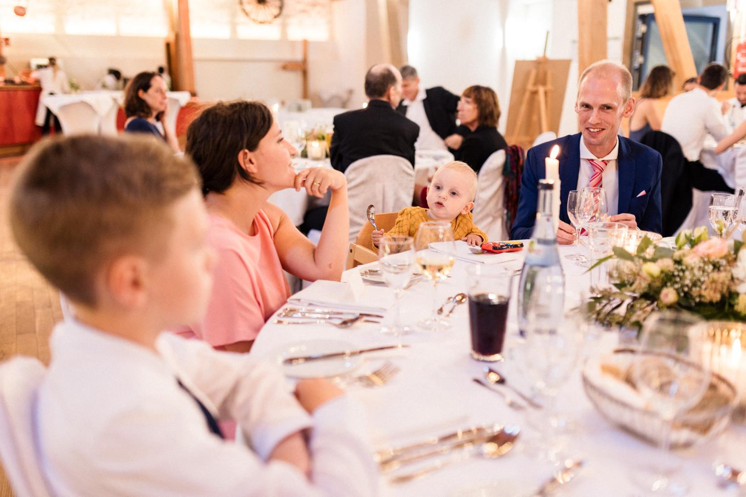 Familie mit Kleinkind am Hochzeitstisch im warmen Kerzenlicht