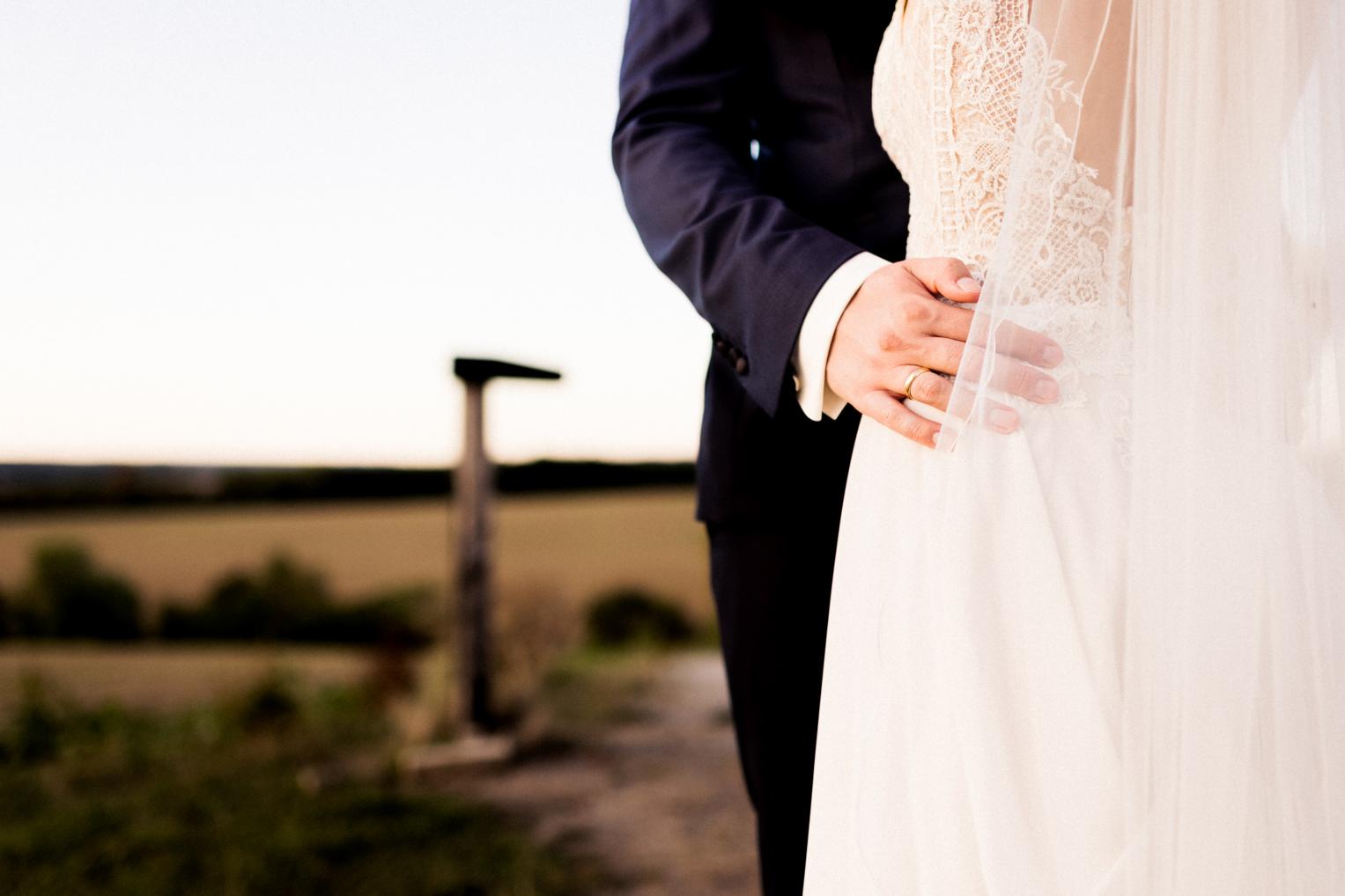 Detail Hand mit Ehering an der Taille der Braut im Feld