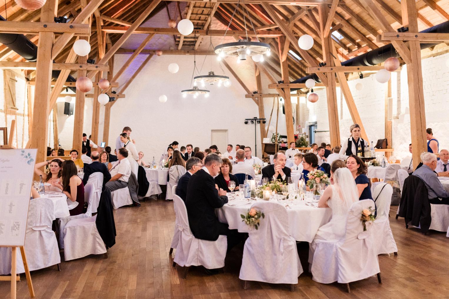 Hochzeitsgäste an festlich gedeckten Tischen im Festsaal