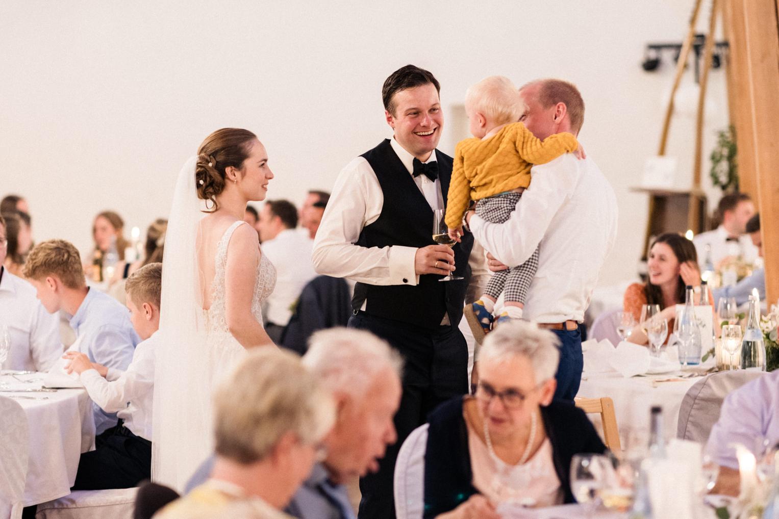 Bräutigam herzt das Baby eines Freundes im Festsaal
