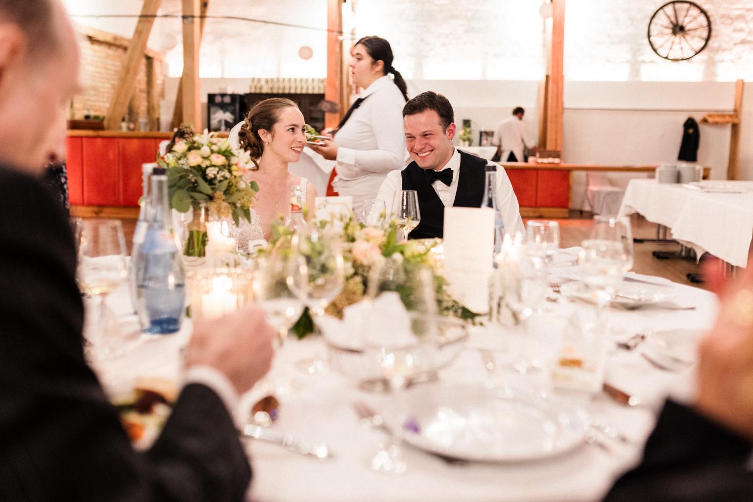 Brautpaar lacht am Hochzeitstisch im Kerzenschein