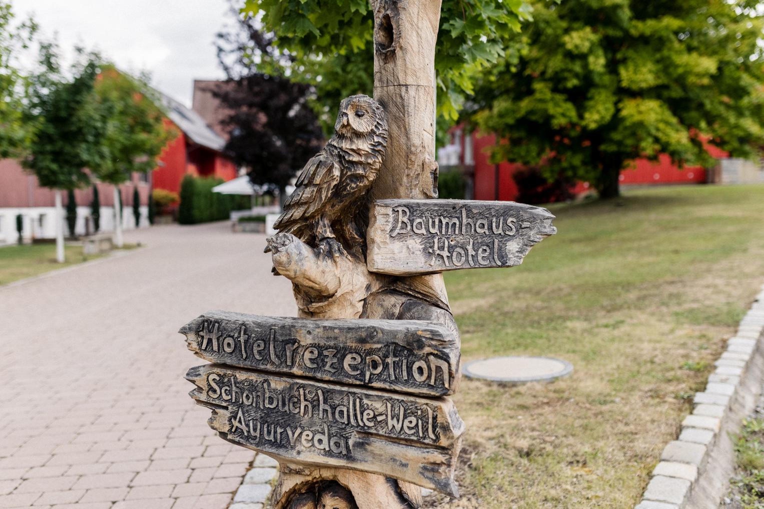 Wegweiser-Skulptur mit Eule am Eingang des Baumhaushotels OaseWeil