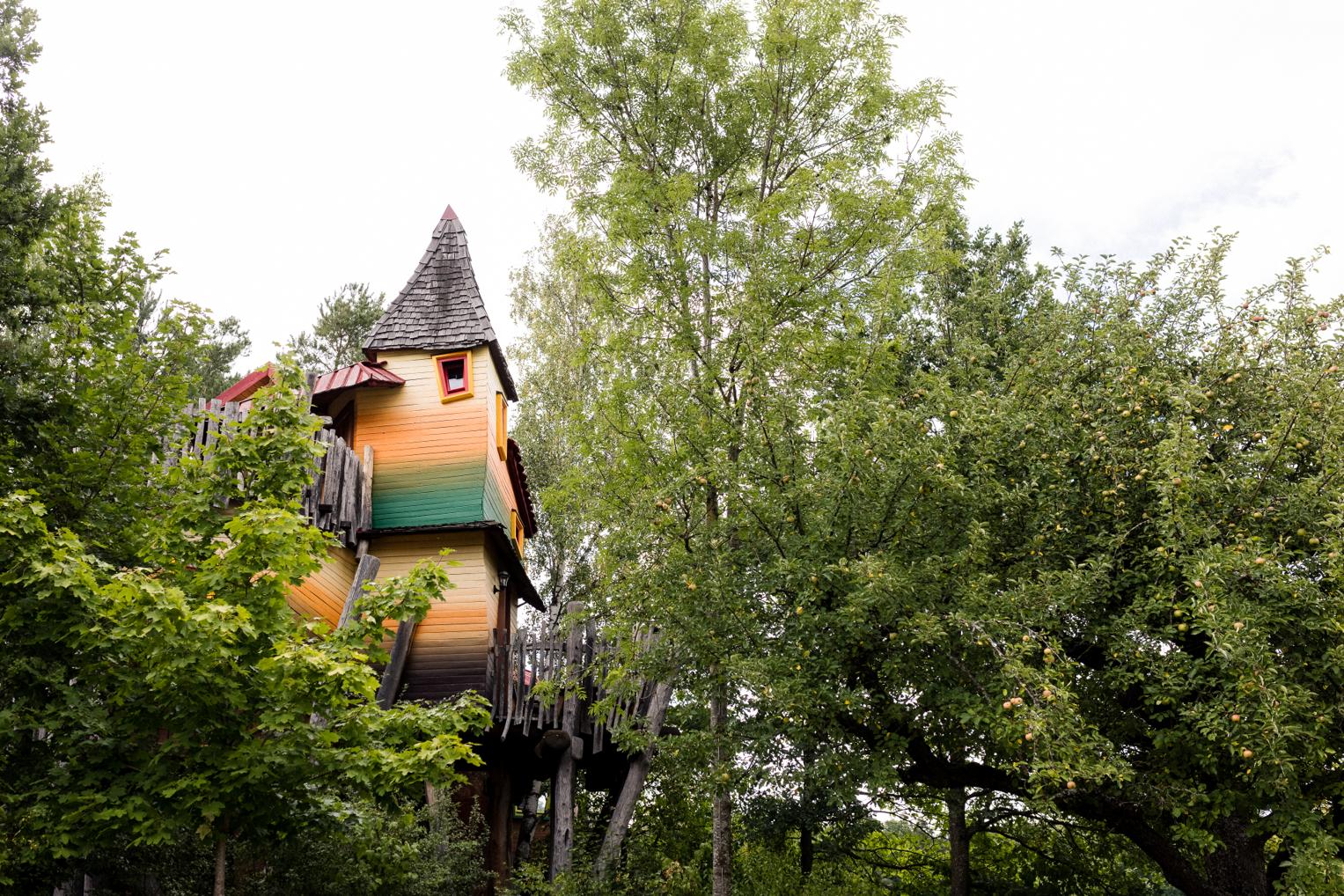 Märchenhaftes Baumhaus mit Spitzdach zwischen Bäumen im Baumhaushotel OaseWeil