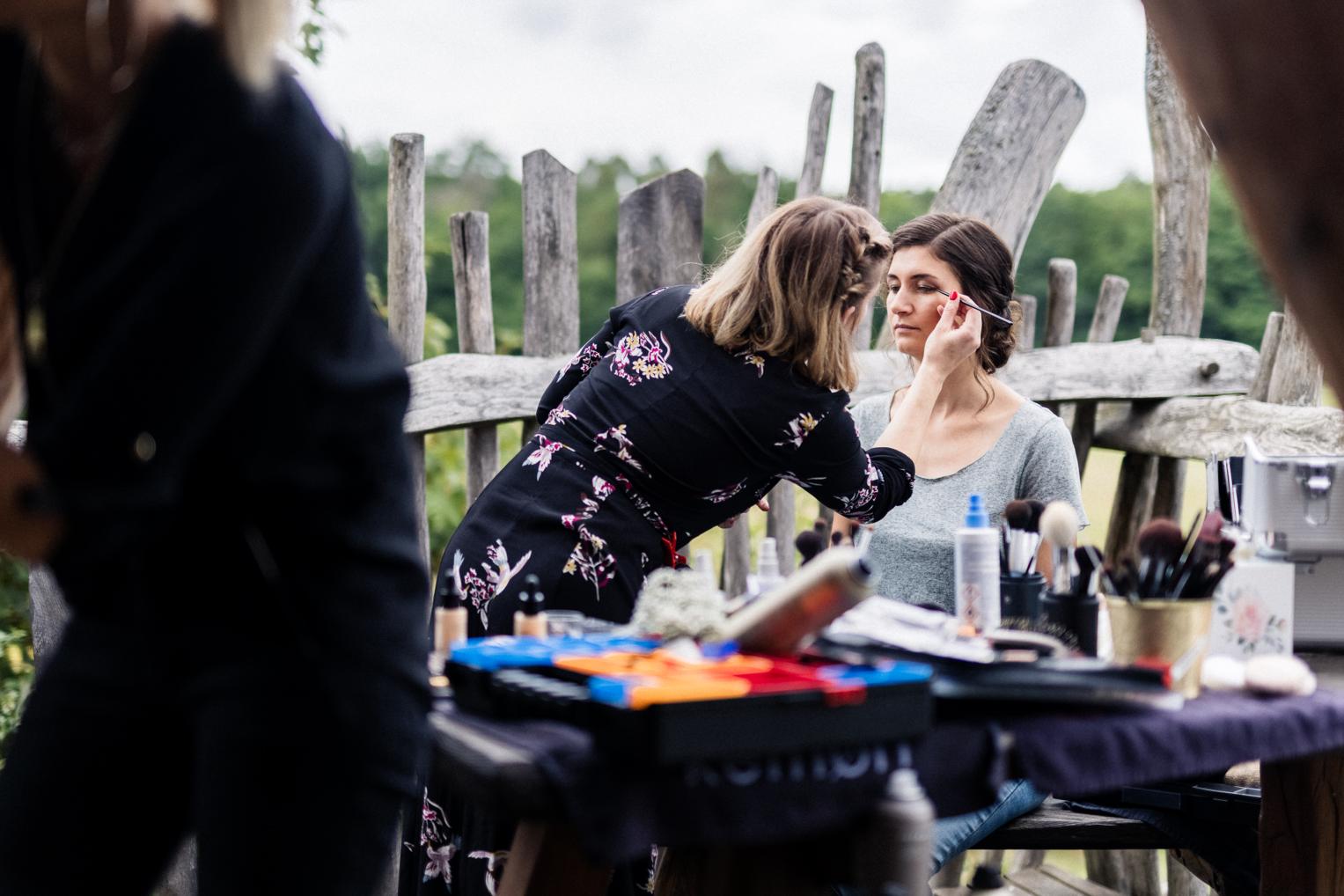 Visagistin trägt Make-up auf der Terrasse des Baumhaushotels bei der Braut auf