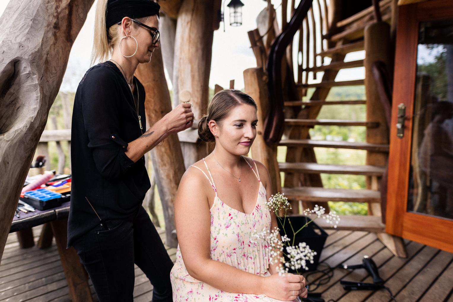 Stylistin steckt einer Brautjungfer die Haare am Baumhaushotel OaseWeil