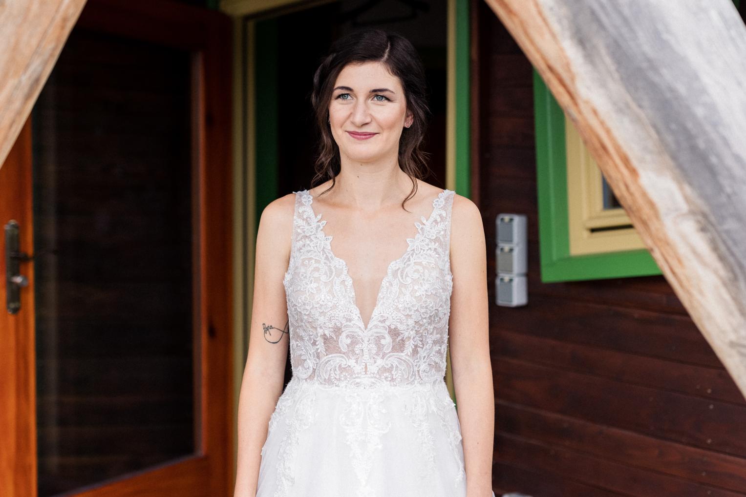 Braut im Spitzenkleid vor dem farbenfrohen Eingang des Baumhaushotels OaseWeil