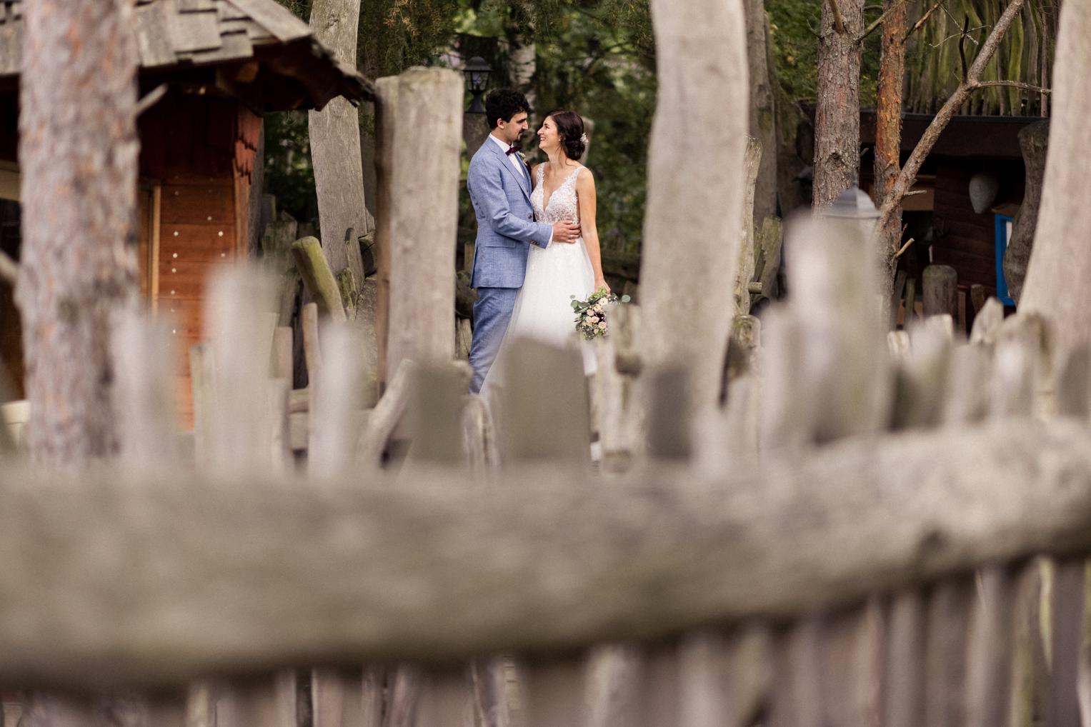 Brautpaar hinter dem Holzzaun des Baumhaushotels OaseWeil bei der Fotosession