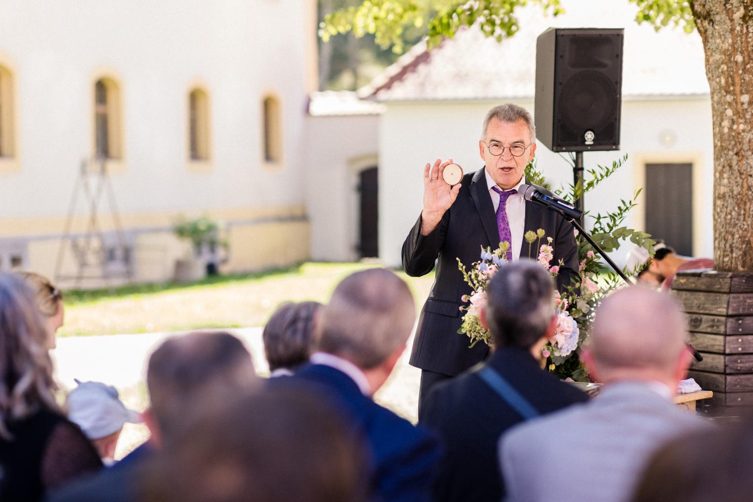 Freier Redner zeigt den Ehering bei der Freien Trauung im Innenhof Schloss Ehrenfels