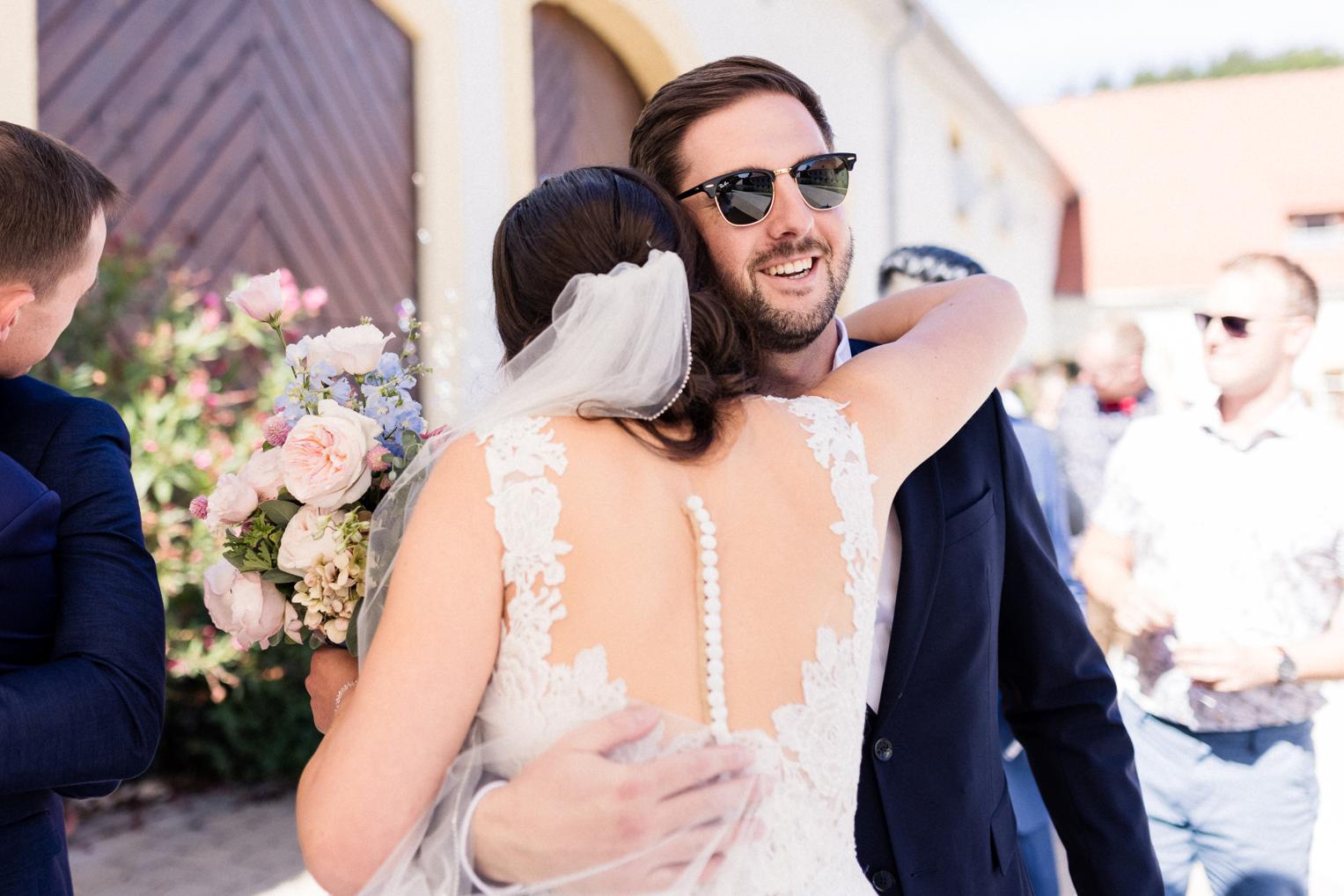 Braut und Freundin lachen und umarmen sich nach der Freien Trauung im Innenhof