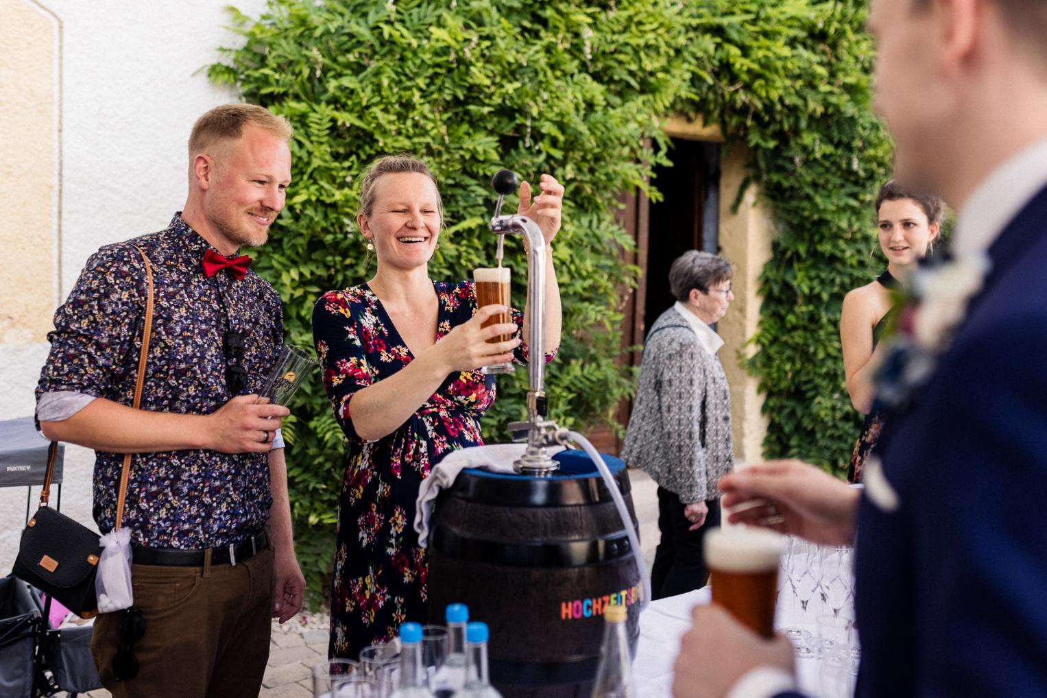 Gäste zapfen gemeinsam das Hochzeitsbier beim Empfang im Innenhof Schloss Ehrenfels