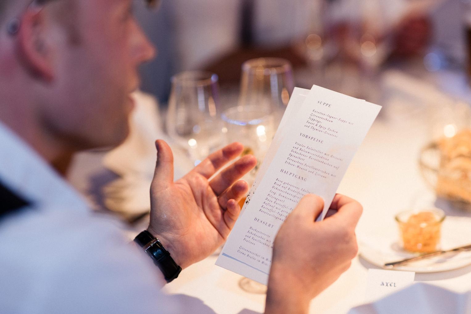 Gast liest Menükarte beim Hochzeitsdinner im Bankettsaal Schloss Ehrenfels