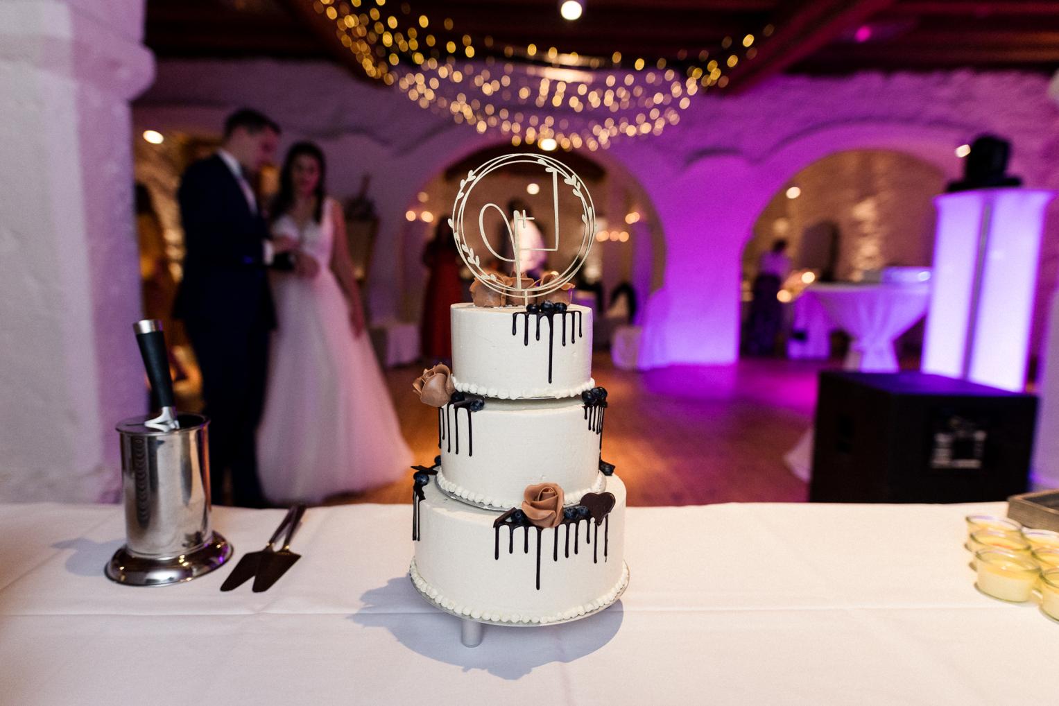 Dreistöckige Hochzeitstorte mit Drip-Deko im beleuchteten Saal Schloss Ehrenfels