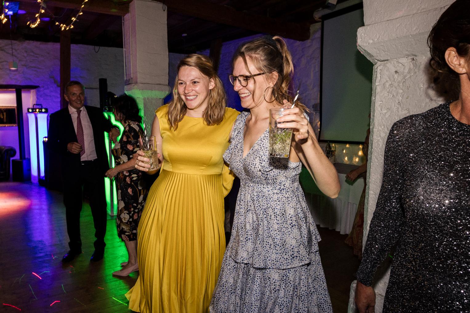 Zwei Frauen tanzen lachend zusammen auf der Hochzeitsparty im Saal Schloss Ehrenfels