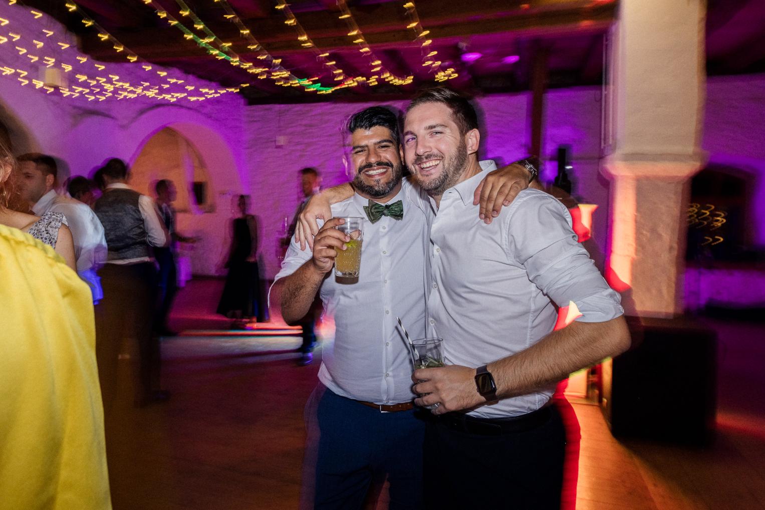 Zwei Männer tanzen lachend zusammen auf der Hochzeitsparty Schloss Ehrenfels
