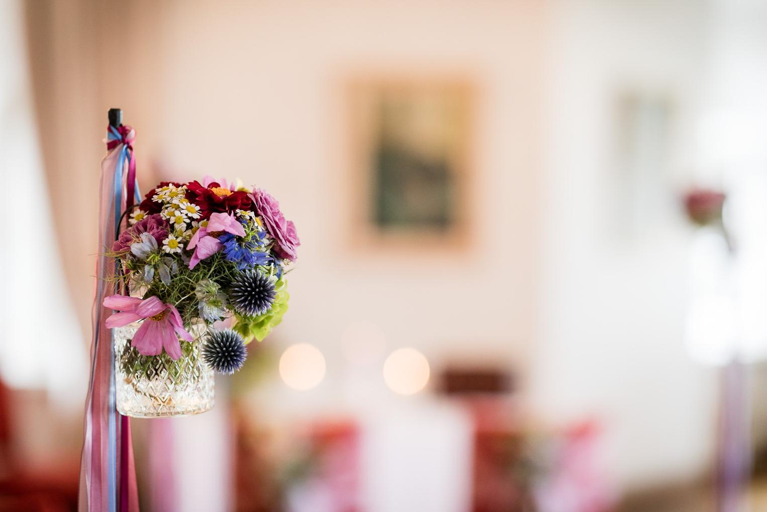 Bunte Wiesenblumen mit Seidenbändern als Stuhldeko im Schloss