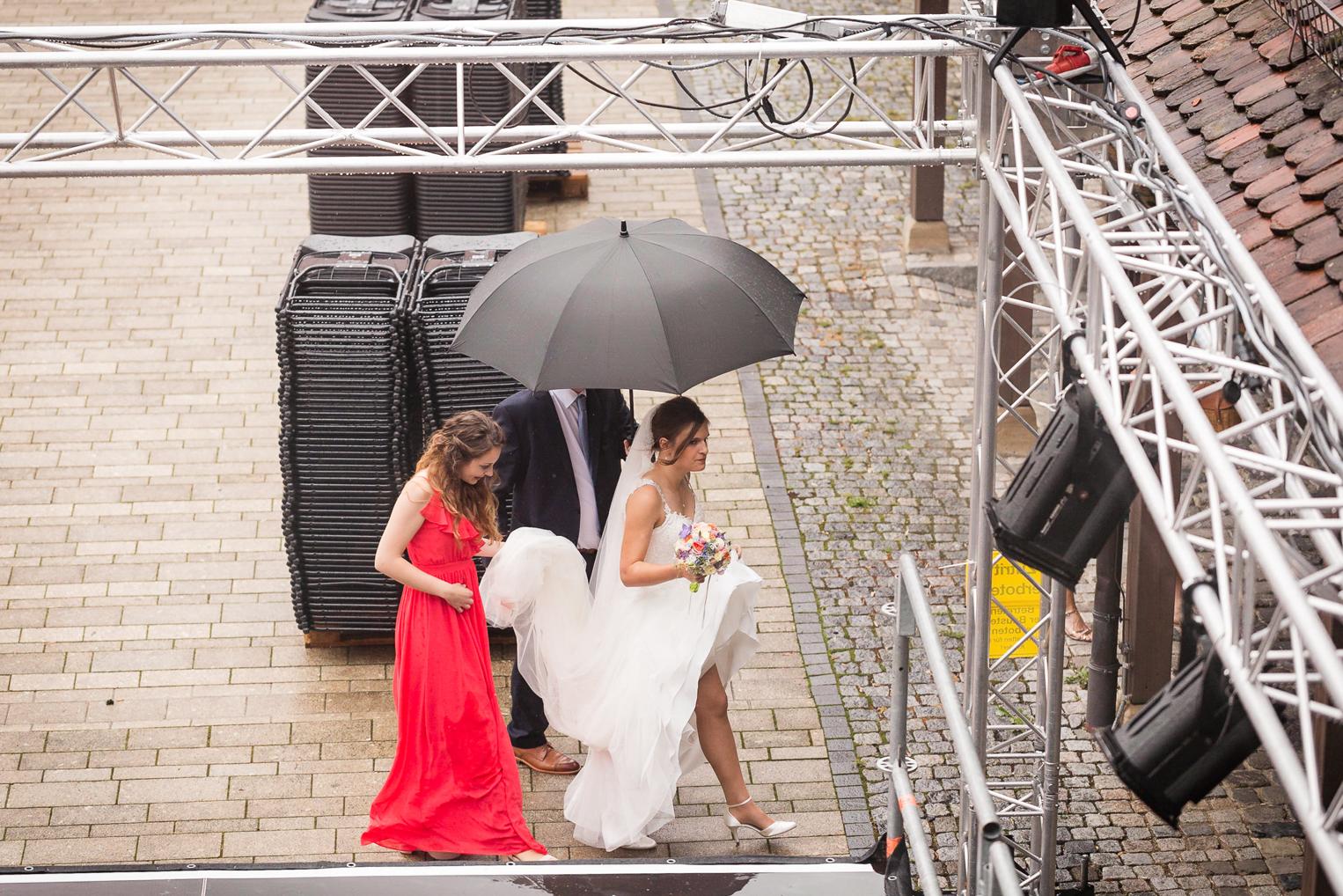 Brautjungfer hält den Regenschirm für die Braut am Schlossvorplatz