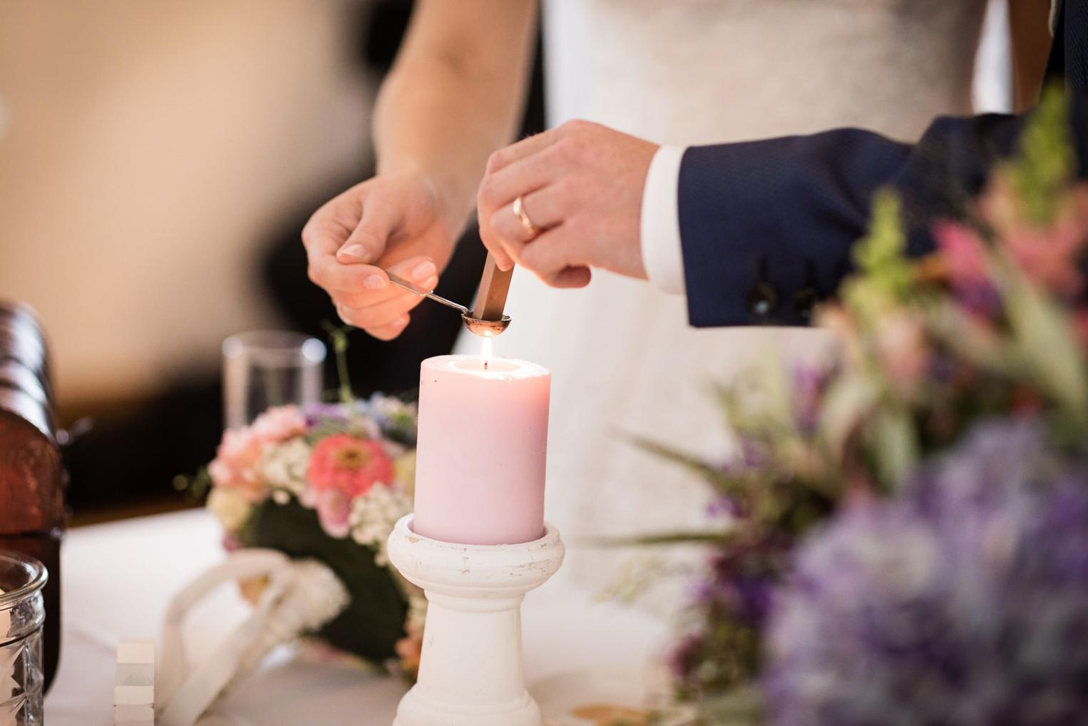 Brautpaar versiegelt Hochzeitsritual mit Wachs an der rosa Kerze