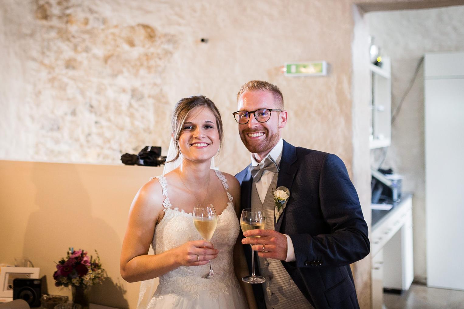 Brautpaar stößt strahlend mit Sektglas auf die Hochzeit an