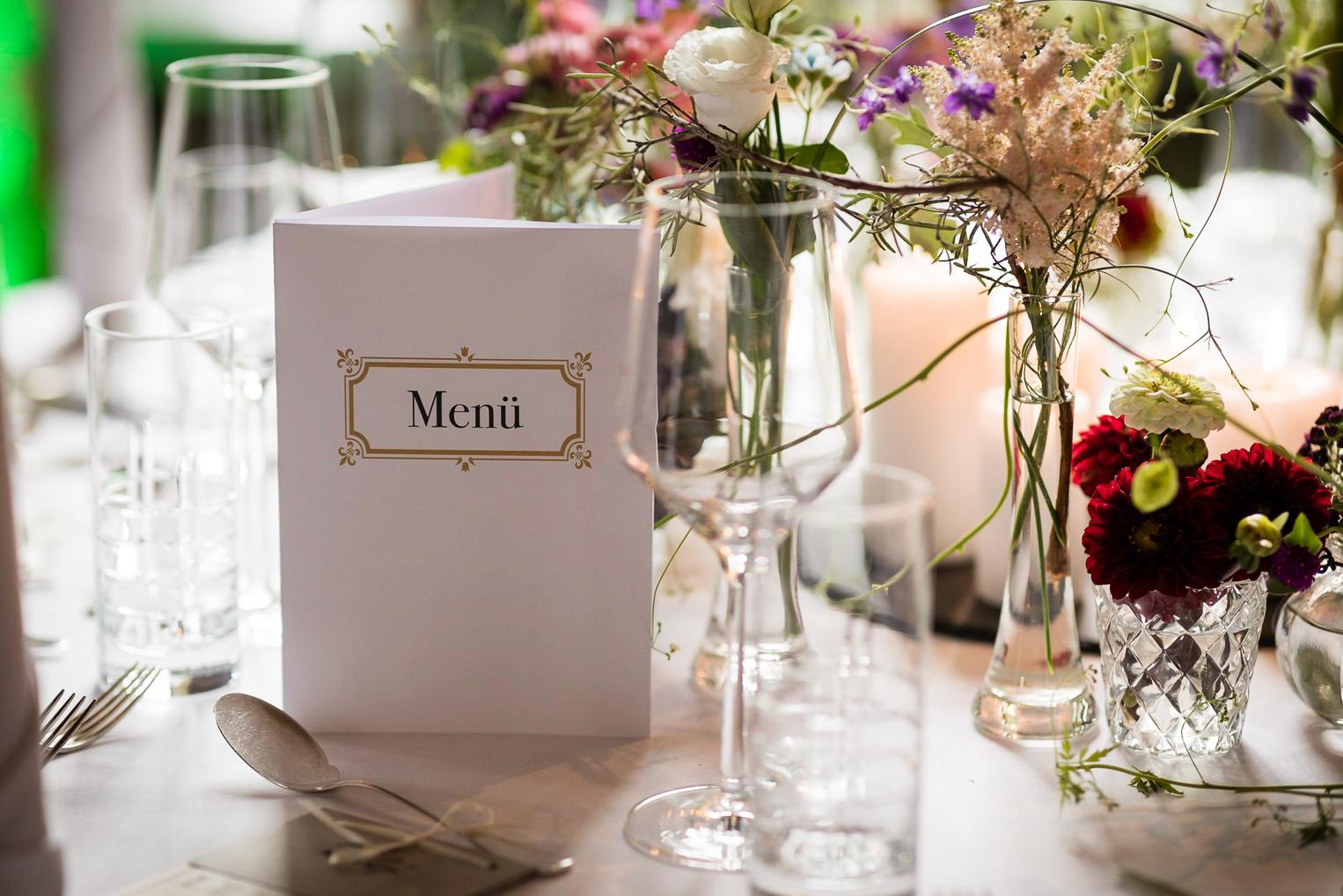Edle Menükarte zwischen Wiesenblumen und Kristallgläsern