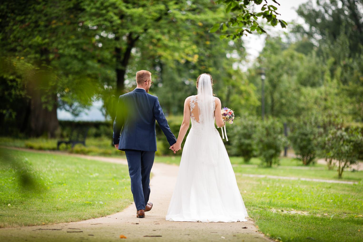 Brautpaar spaziert Hand in Hand durch den Schlosspark