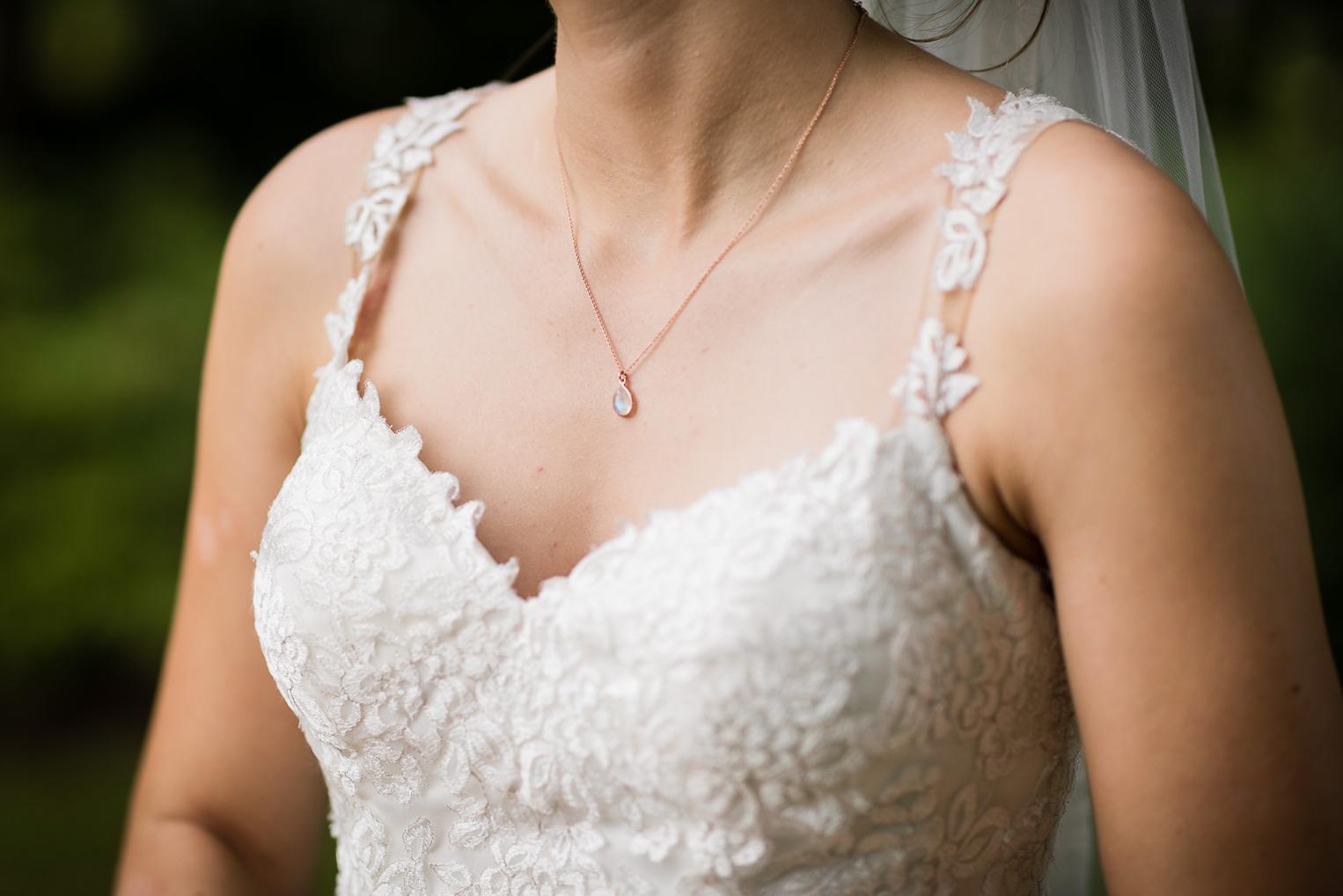 Detail vom Spitzenkleid der Braut mit Kettenanhänger
