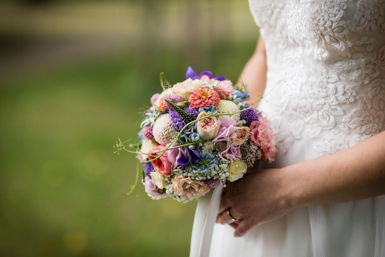 Bunter Brautstrauß mit Wiesenblumen in der Hand der Braut