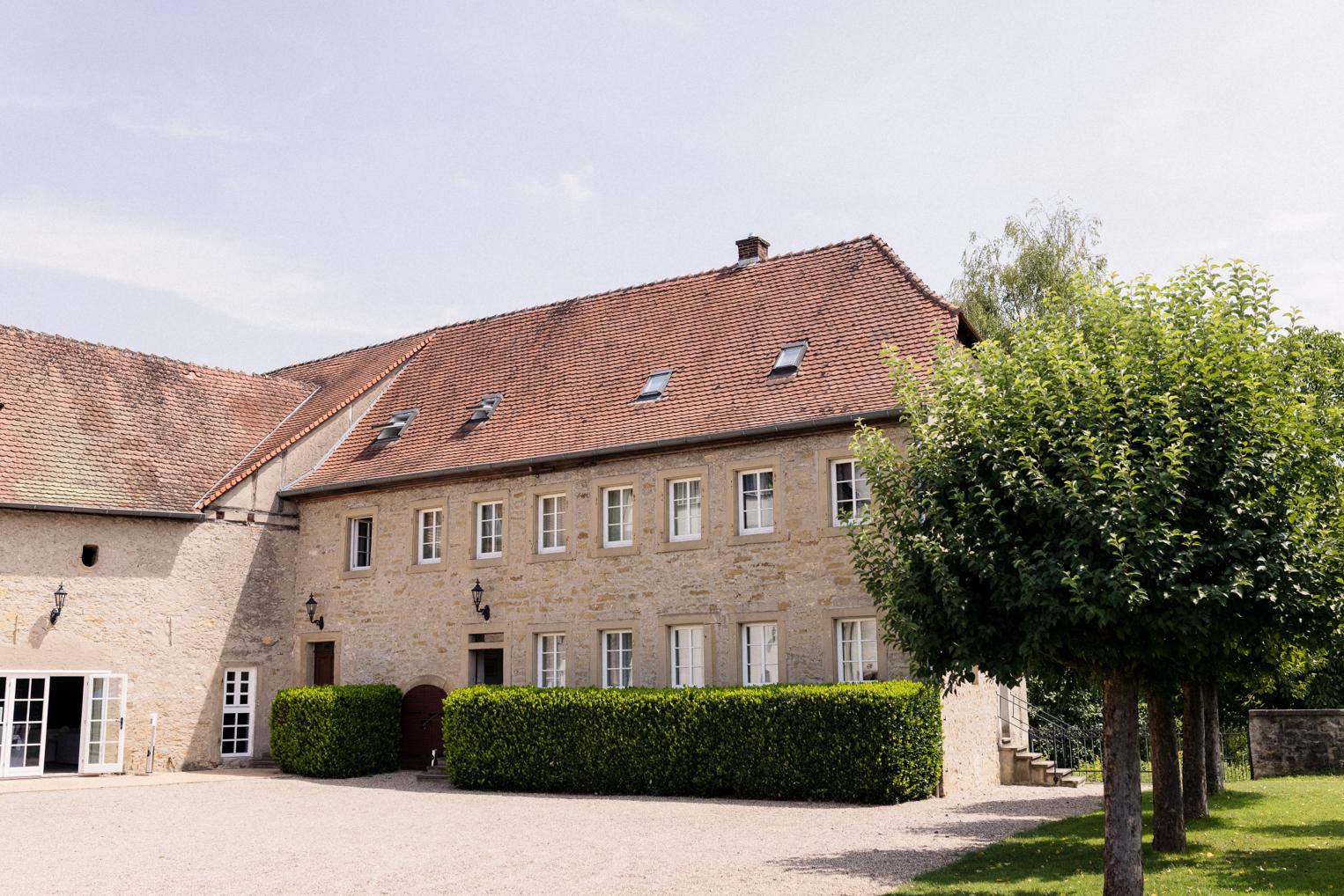 Sandsteinernes Nebengebäude mit Ziegeldach und Buchshecke am Schlosshof – Gästehaus der Location bei Sinsheim