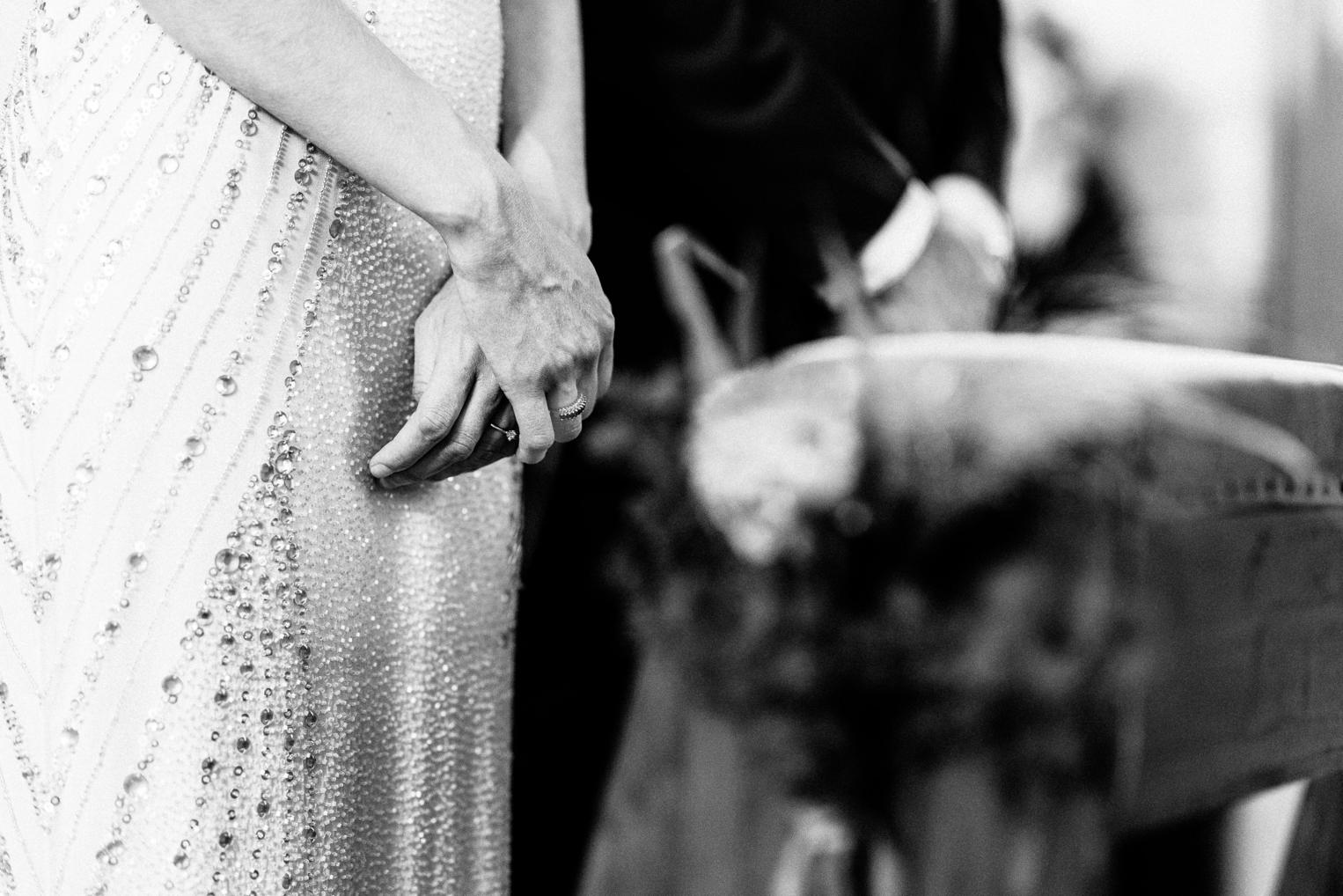 Hand der Braut mit Ehering am perlenbestickten Kleid – stiller Moment während der Trauzeremonie
