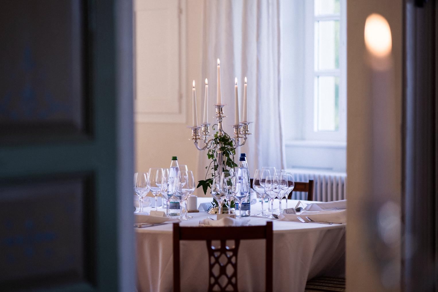 Blick durch die Flügeltür auf einen festlich gedeckten Tisch mit Silberleuchter im Schlosssaal
