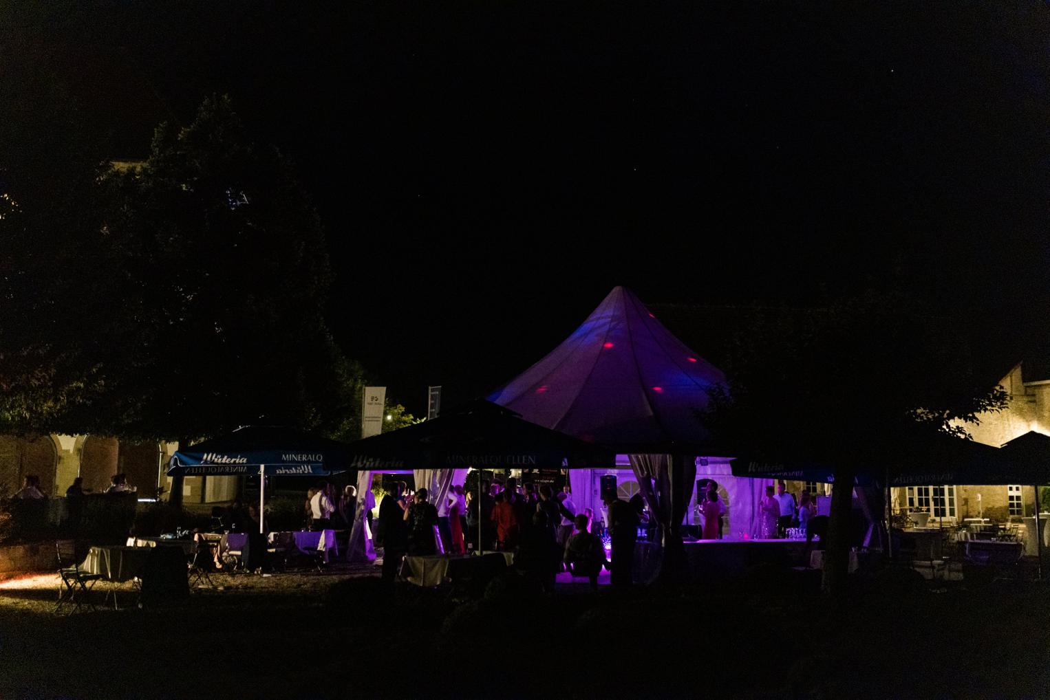 Beleuchtetes Partyzelt im Schlosshof bei Nacht – die Hochzeitsfeier auf Schloss Neuhaus klingt aus