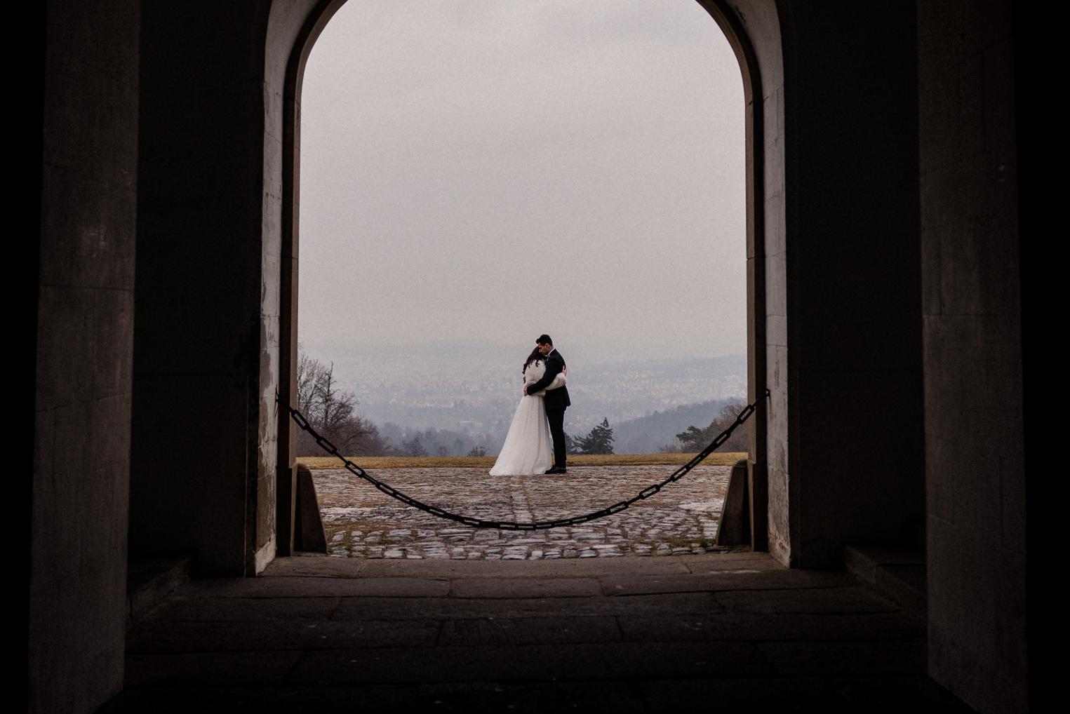 Brautpaar unter dem Torbogen von Schloss Solitude mit Blick auf die neblige Aussicht über Stuttgart