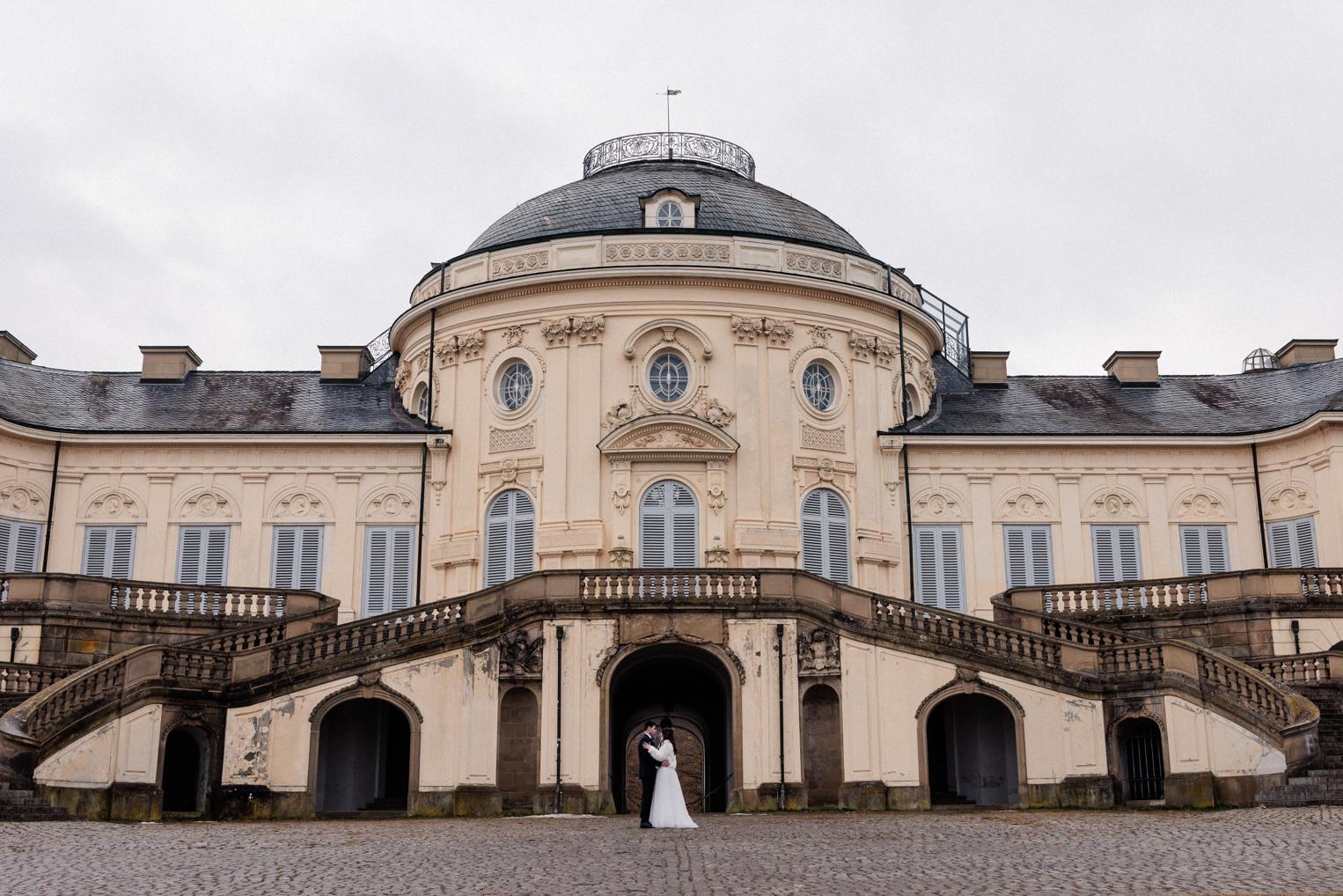 Weitwinkelaufnahme der Schlossfassade von Schloss Solitude in Stuttgart, Brautpaar klein im Torbogen