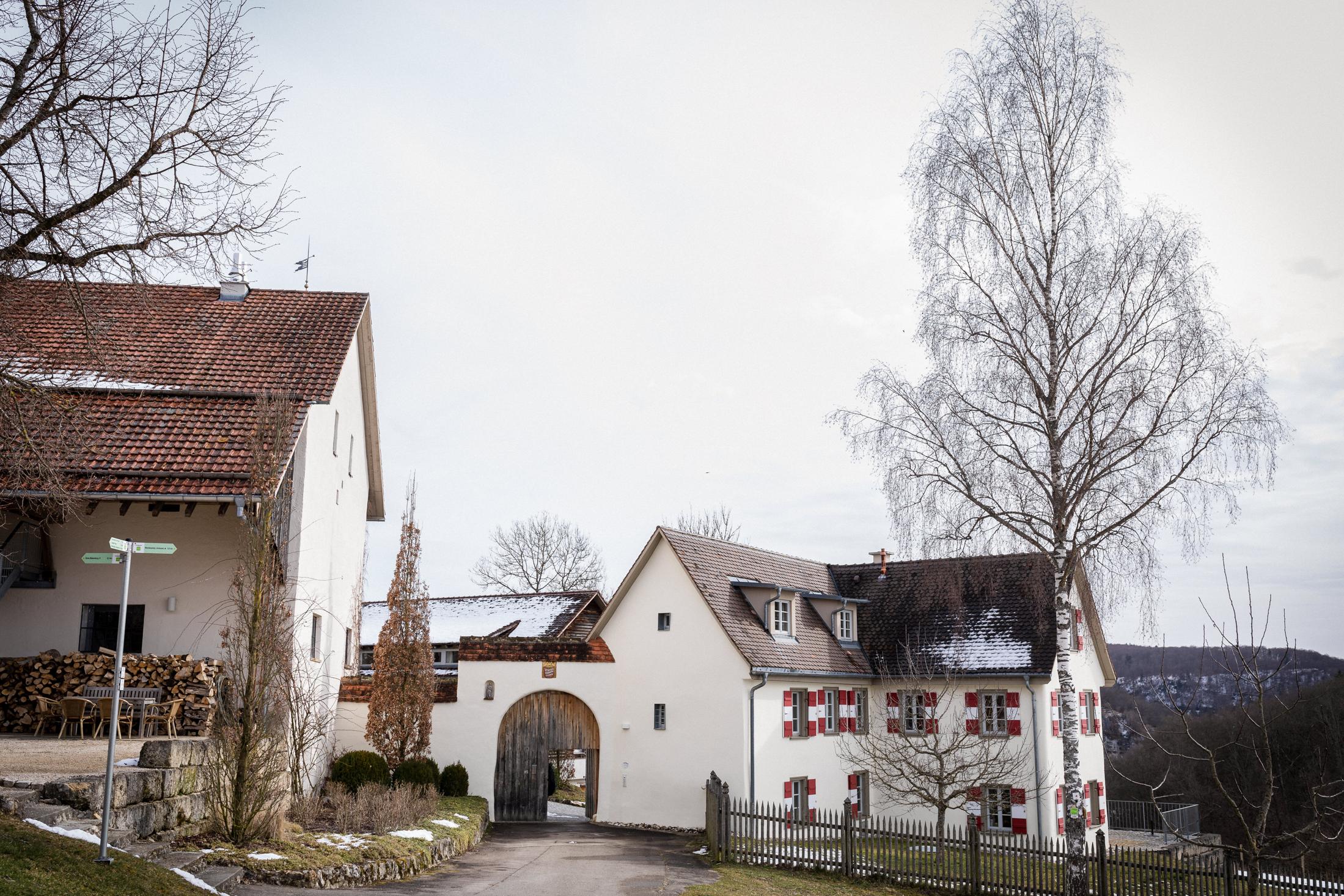 Hofgut Maisenburg im Winter mit Toreinfahrt und schneebedeckten Dächern
