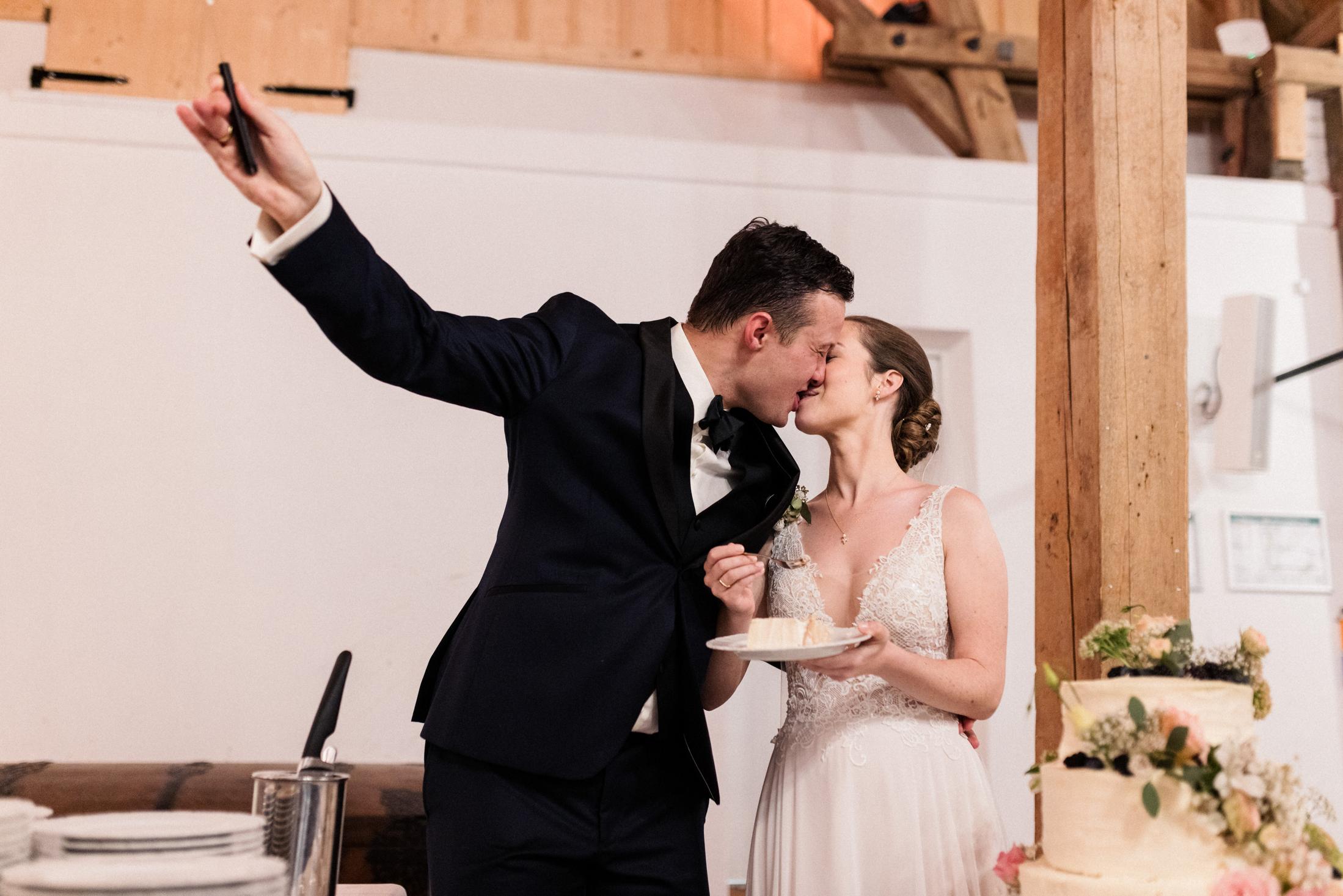 Brautpaar küsst sich beim Selfie am Hochzeitstortenbuffet