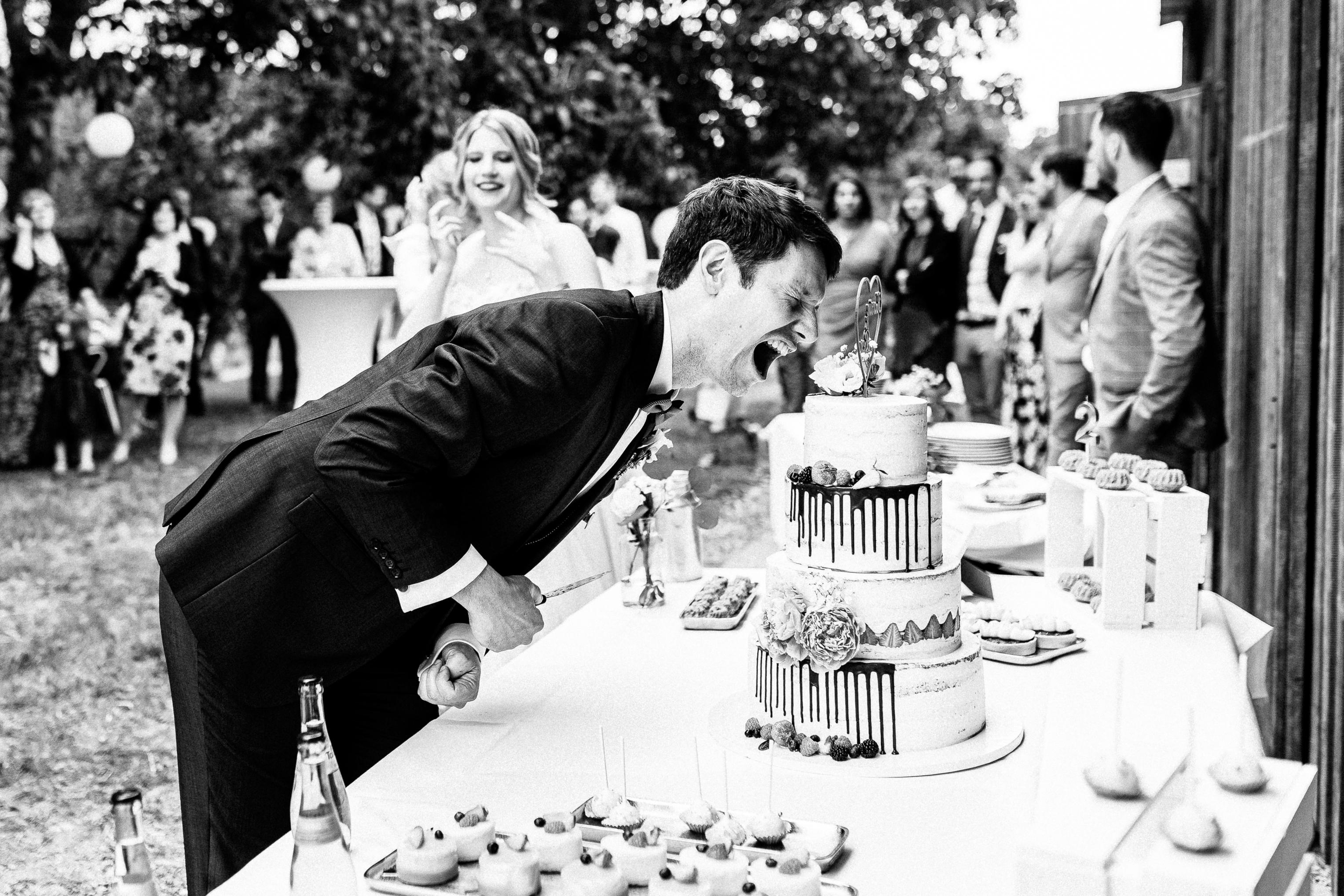 Bräutigam lacht beim Anschneiden der Hochzeitstorte im Freien am Lindenhof Mötzingen
