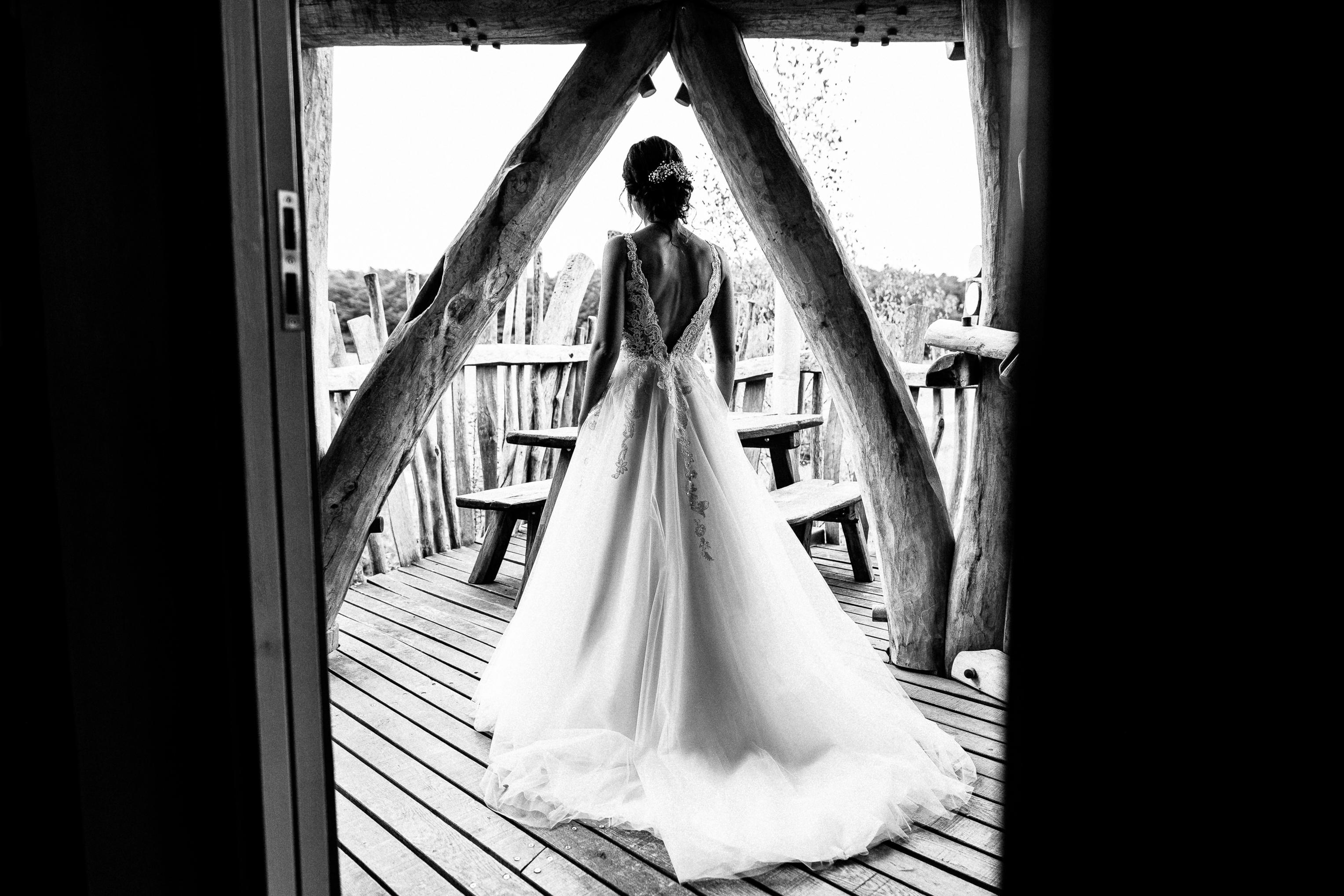 Braut im Hochzeitskleid von hinten auf der Terrasse des Baumhaushotels OaseWeil