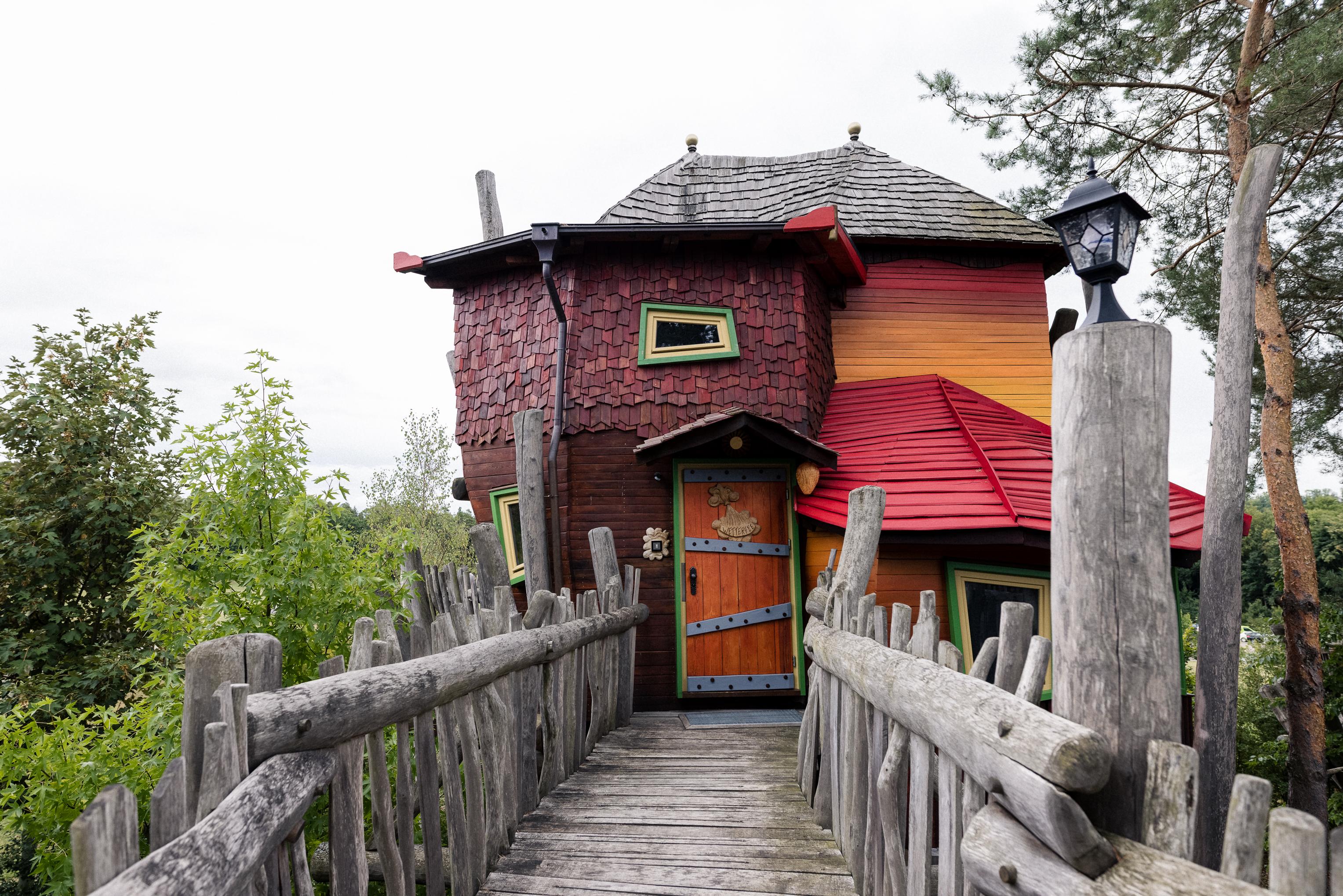 Holzbrücke führt zum bunten Baumhaus mit rotem Dach im Baumhaushotel OaseWeil