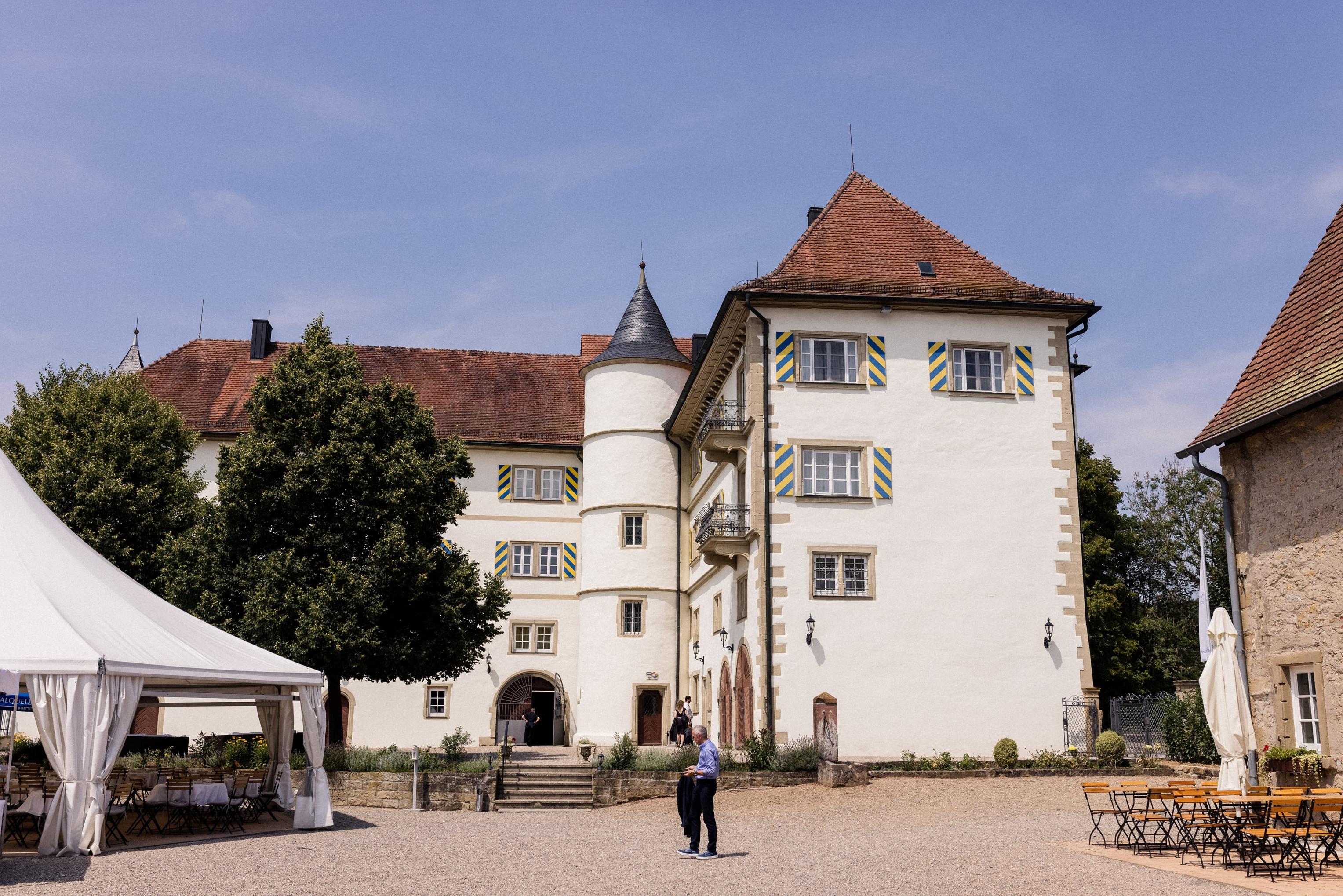 Innenhof von Schloss Neuhaus mit weißem Pavillonzelt und Biertischen – Platz für die Hochzeitsfeier unter freiem Himmel