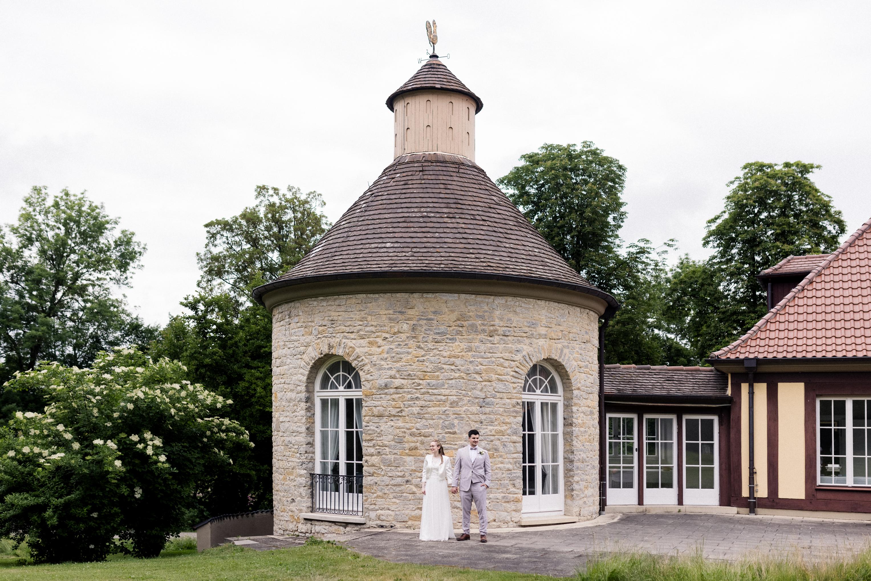 Brautpaar vor dem Turmzimmer der Villa Schwalbenhof – Gesamtansicht mit Turm, Garten und Park