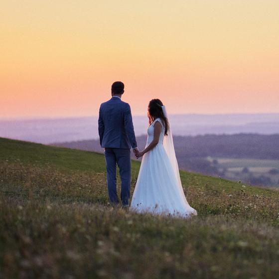 Brautpaar bei einem After-Wedding-Shooting auf einer Wiese im warmen Abendlicht mit Blick in die Ferne