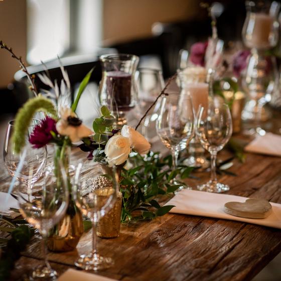 Stilvolle Tischdekoration bei einer Winterhochzeit auf dem Hofgut Maisenburg mit floralen Details, Kerzen und edlem Glas