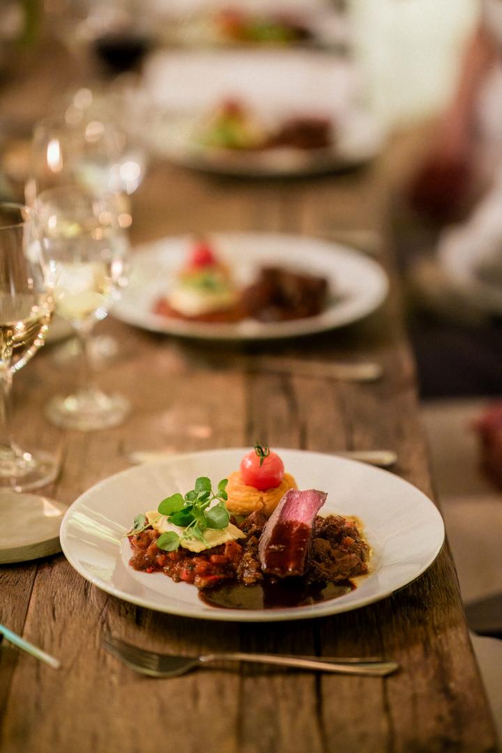 Detailaufnahme eines festlichen Hauptgangs auf der Hochzeit im großen Saal des Hofguts Maisenburg, mit elegant gedecktem Holztisch.