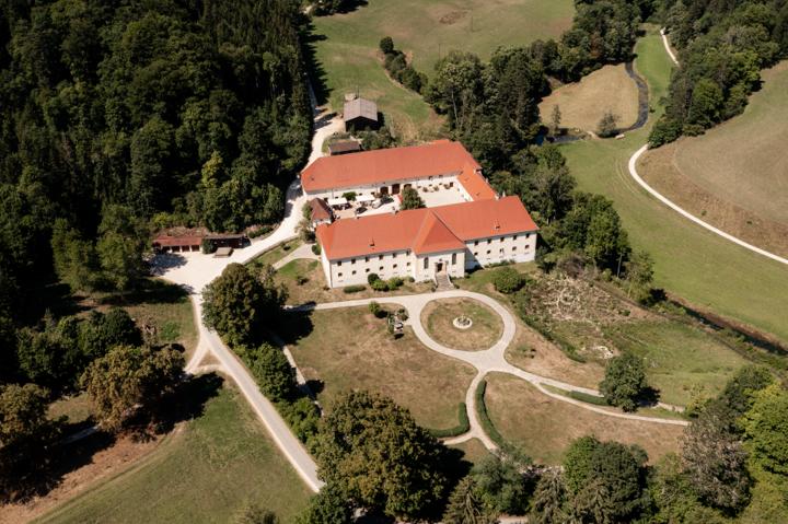 Luftaufnahme von Schloss Ehrenfels, umgeben von weitläufiger Natur und gepflegten Grünflächen.