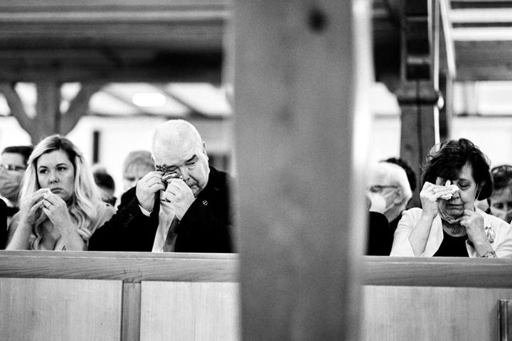 Emotionale Gäste in einer Kirche, die sich Tränen der Rührung während der Trauungszeremonie abwischen.